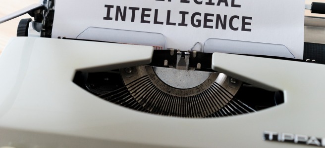 Ein Bild von einer Schreibmaschine mit einem Blatt darin, auf diesem steht "Artificial Intelligence"